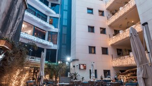 Um hotel com vários andares, áreas de estar ao ar livre, varandas com luzes de cordão e um restaurante à vista.