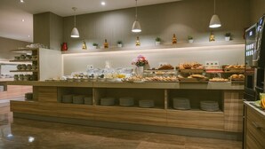 Disposição de buffet com diversos alimentos, pratos e uma geladeira.