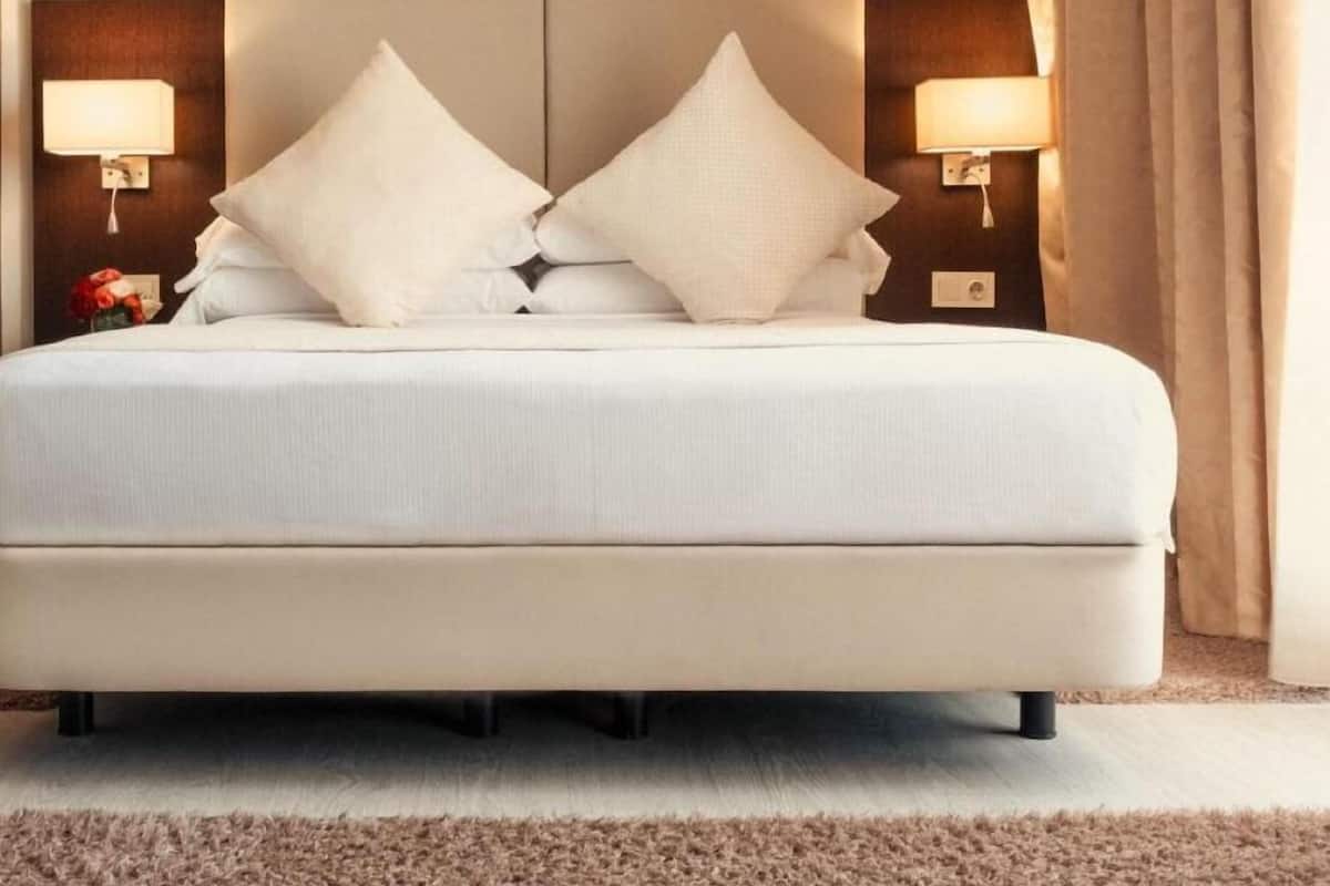 A large bed with a headboard, two bedside lamps, and a neutral color scheme.