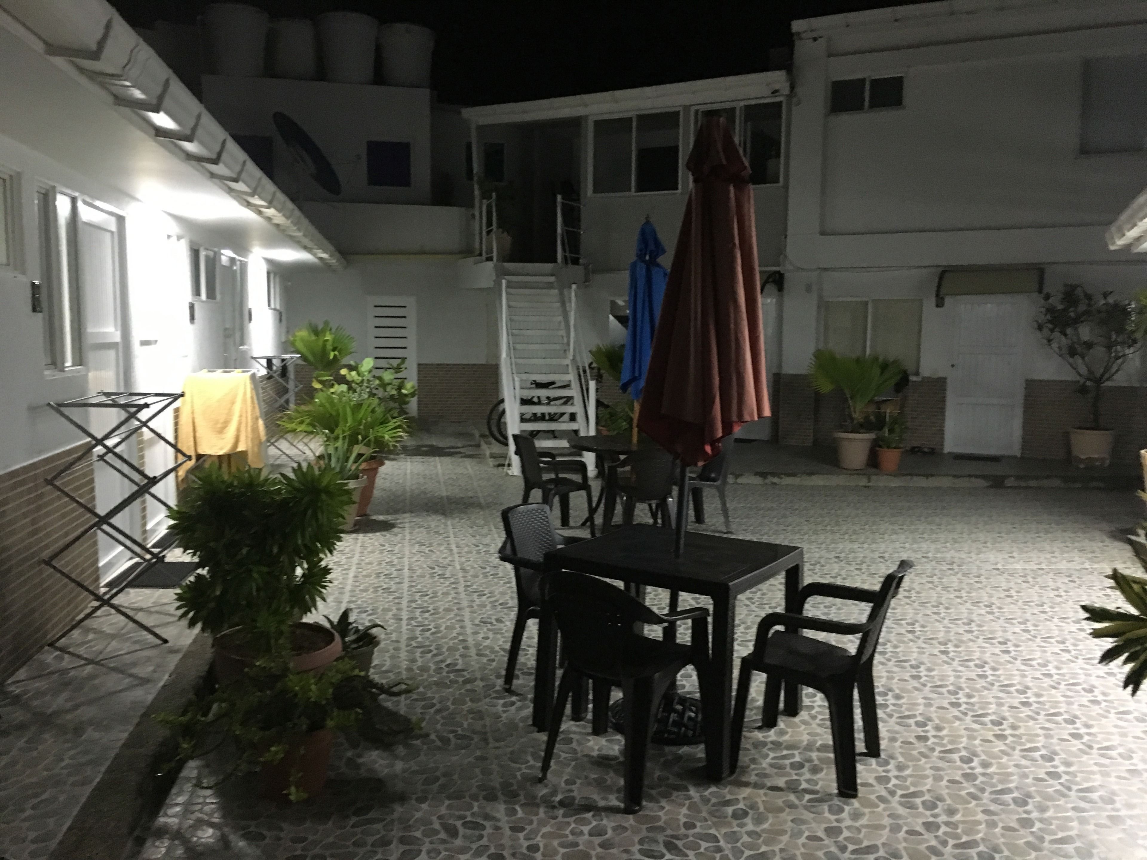 A courtyard with a table and chairs, potted plants, and a drying rack.