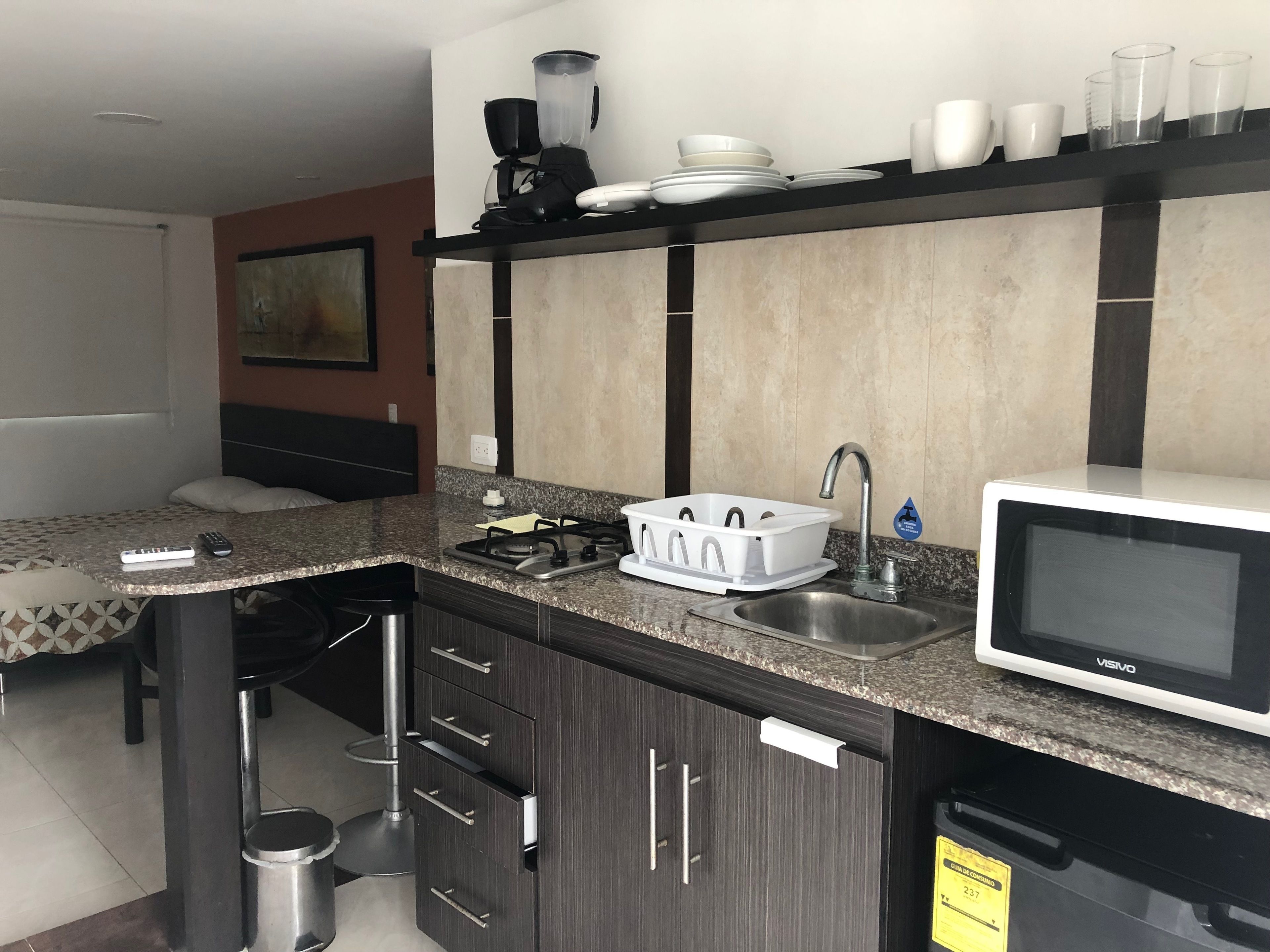 A compact kitchen with a gas stove, a sink, a microwave, and a coffee maker on the countertop.