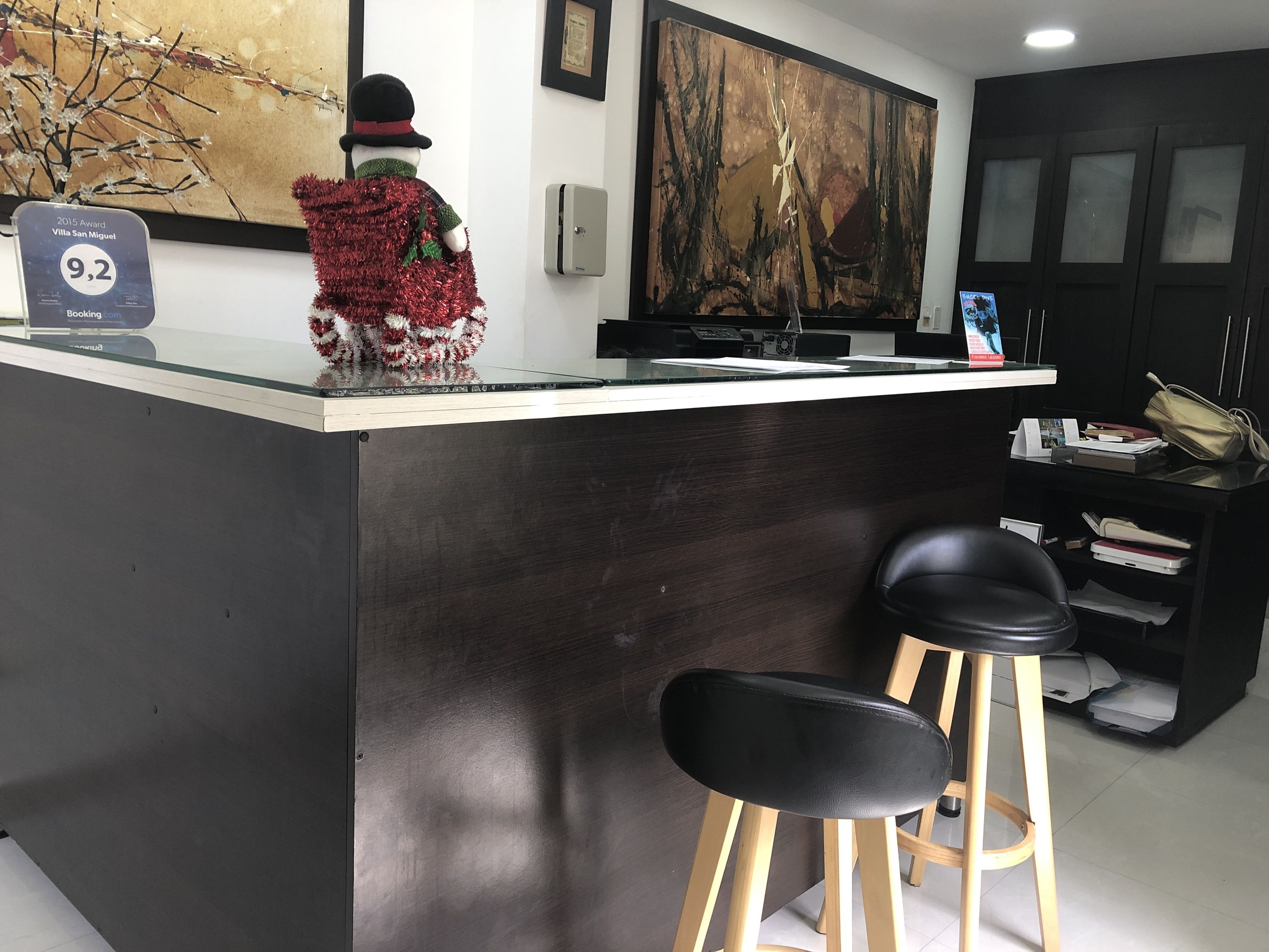 A modern bar area with a glass counter, a large abstract painting, and a snowman decoration.