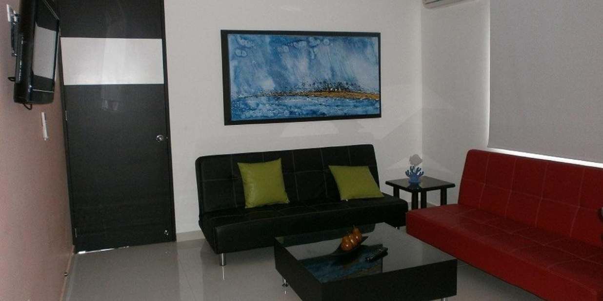 A modern living room with a black sofa, a red sofa, and a painting on the wall.