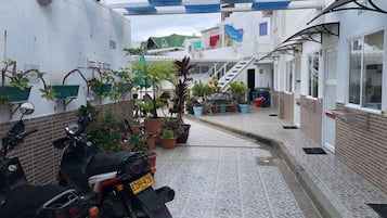 Stroll through this charming outdoor corridor, lined with potted plants and leading to a building entrance with a staircase.