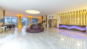 A hotel reception area with a modern design, including a reception desk, seating area, and a view of the outside.