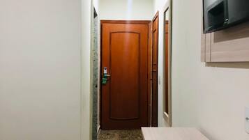 A hallway with a wooden door, a television mounted on the wall, and a wooden table.