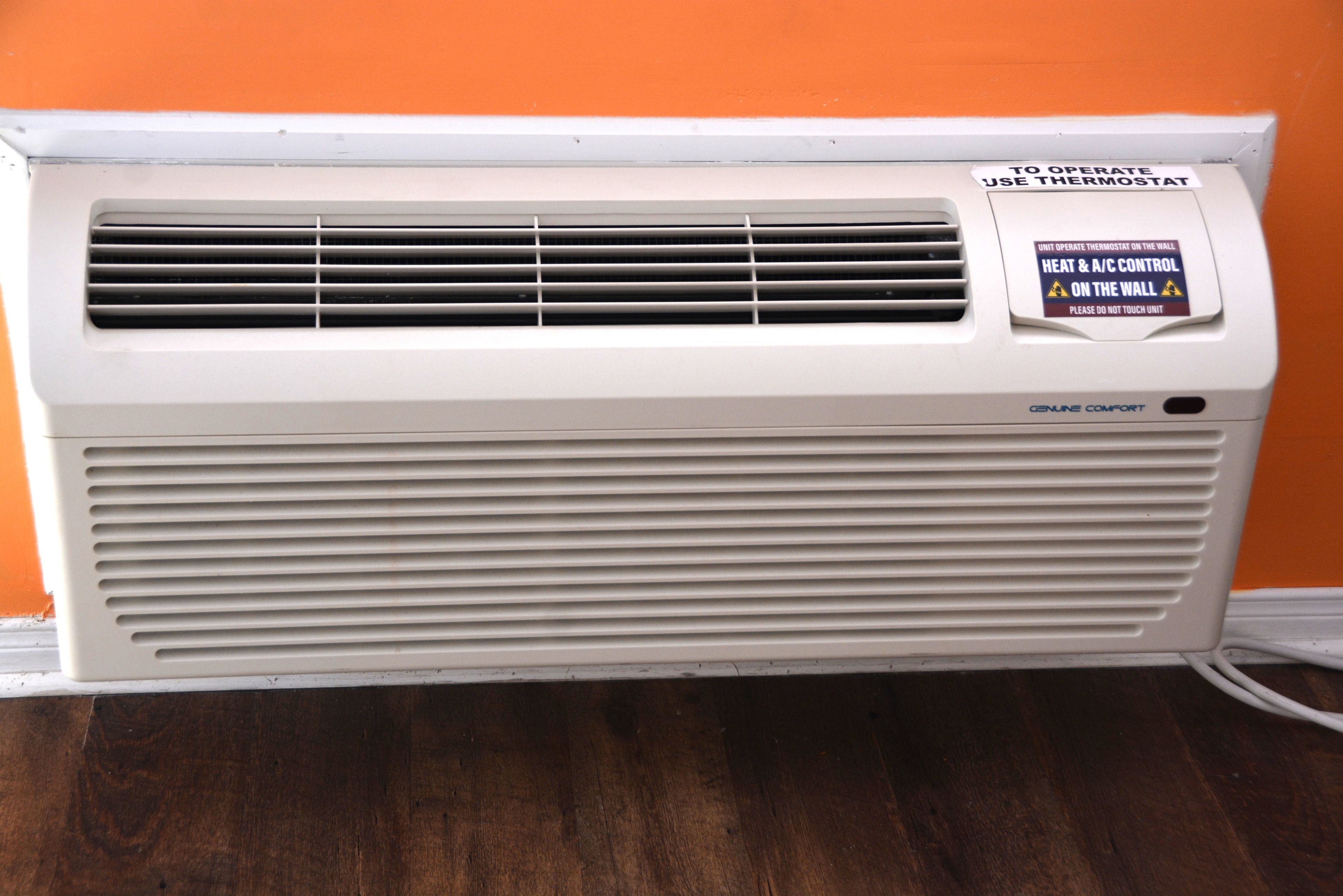 A white air conditioning unit with a warning label and a Genuine Comfort logo.