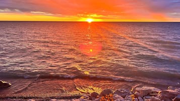 A sunset over the ocean with waves reflecting the colors of the sky.