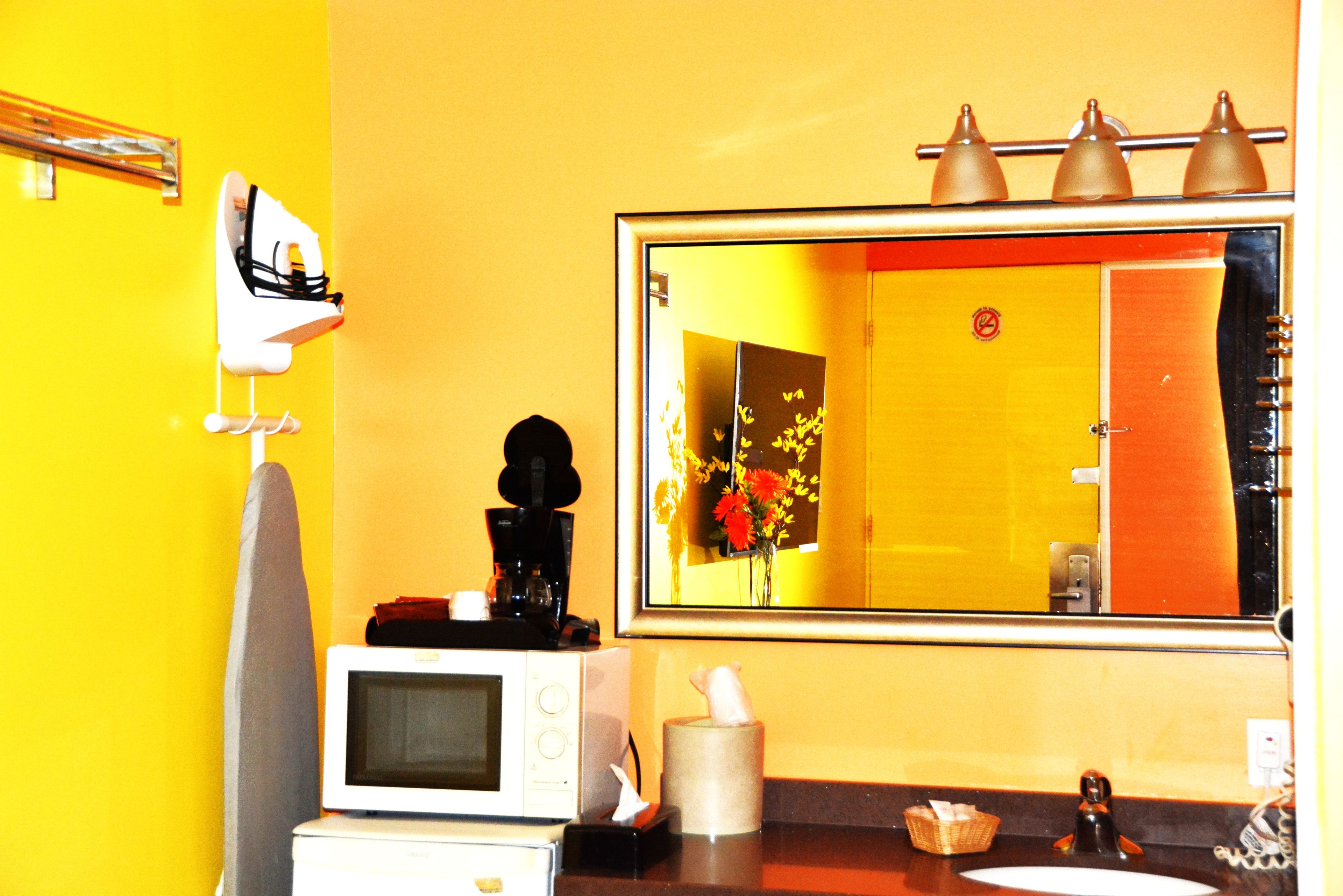 A bathroom with a large mirror, a towel rack, a microwave, and a sink.