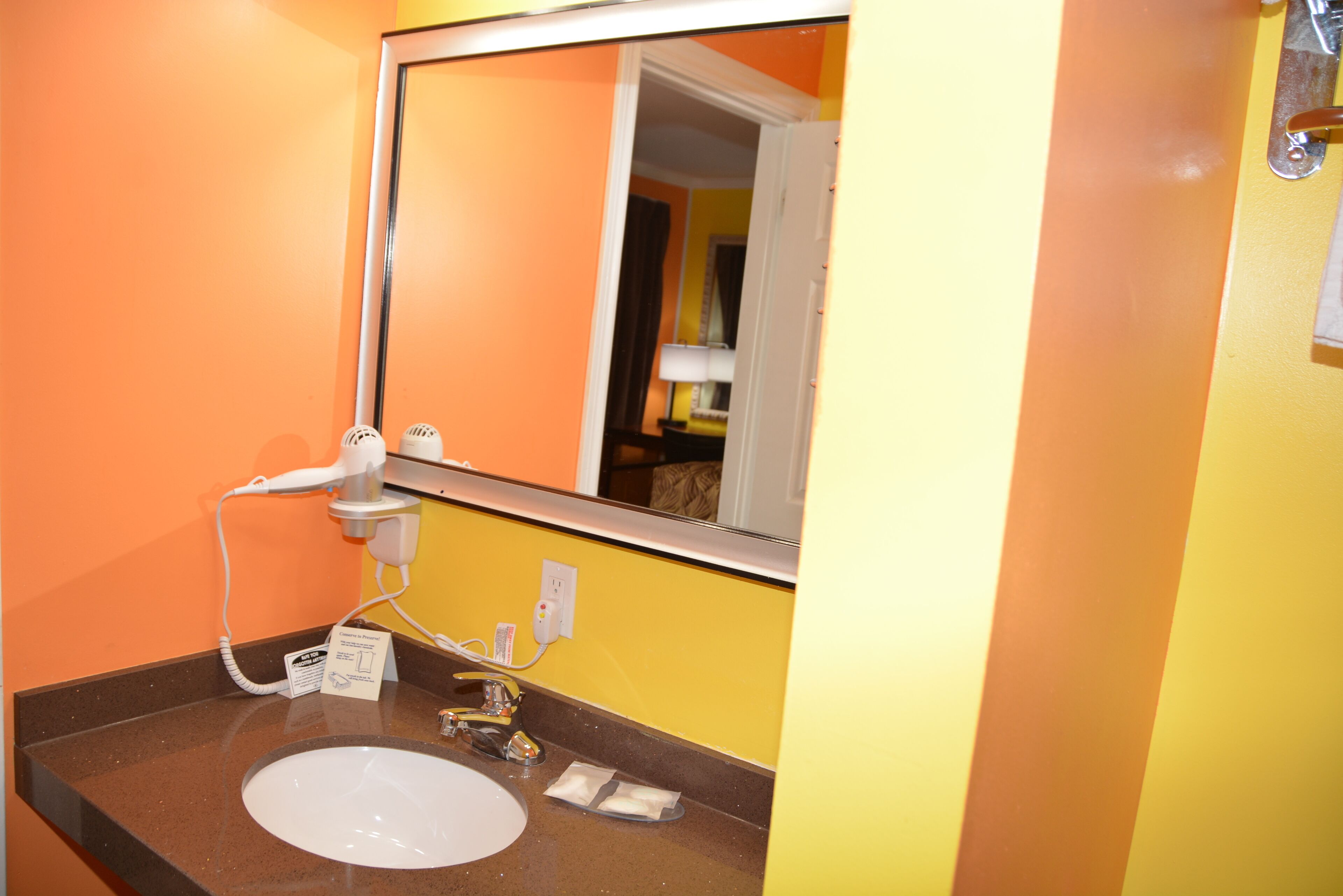Un baño con un lavamanos blanco, un espejo y un dispensador de toallas.