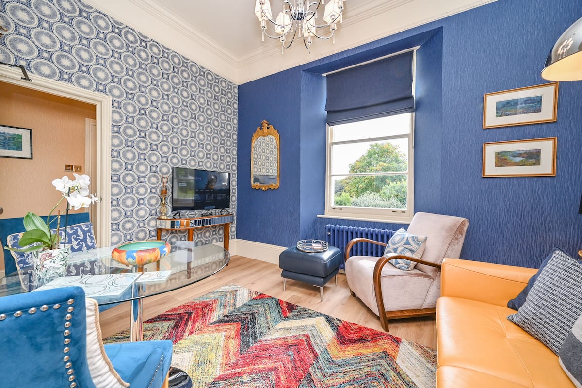 A living room with a patterned wallpaper, a television, a sofa, and a coffee table.