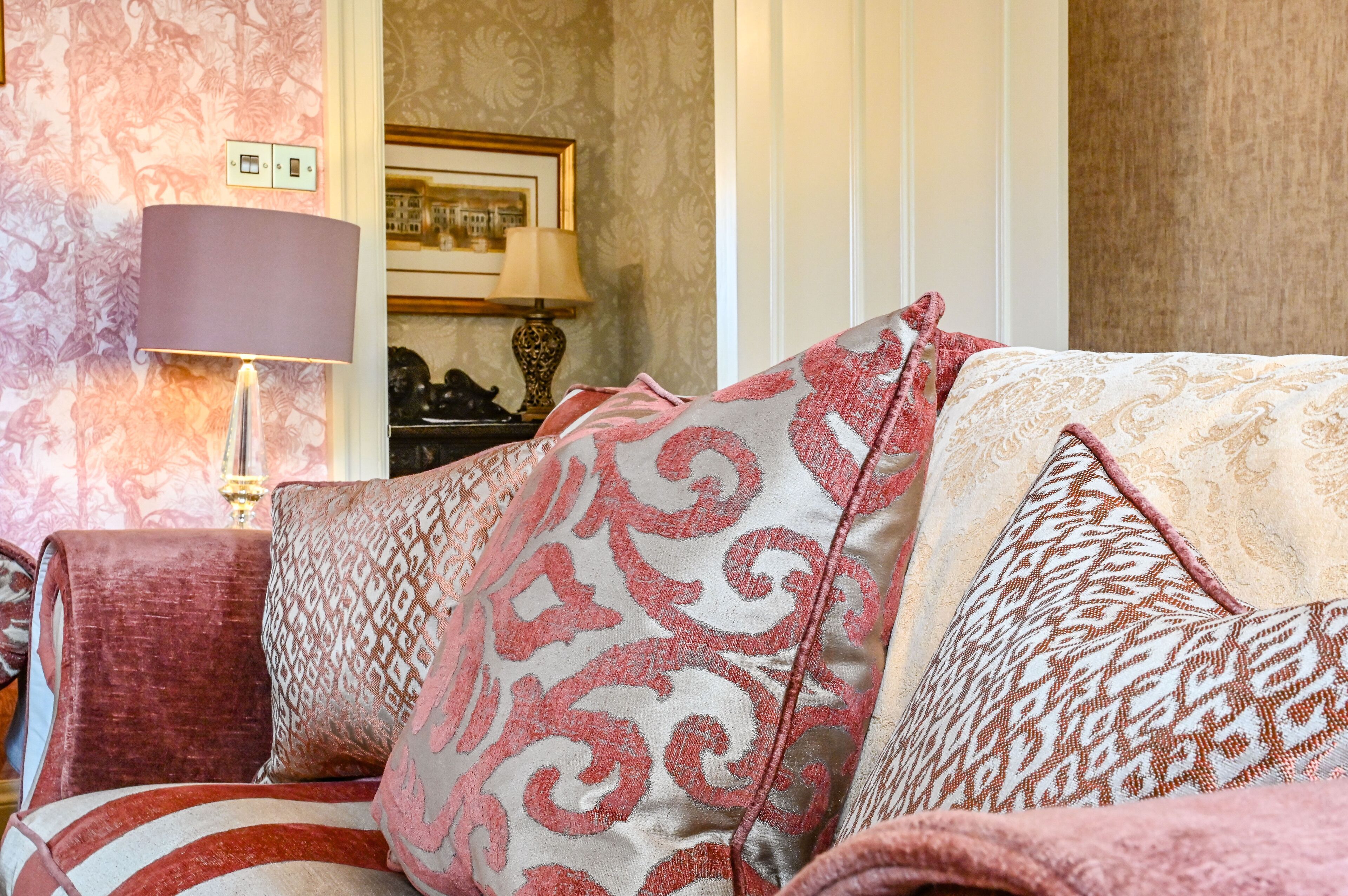 A room with a patterned sofa, a lamp, and a framed picture on the wall.