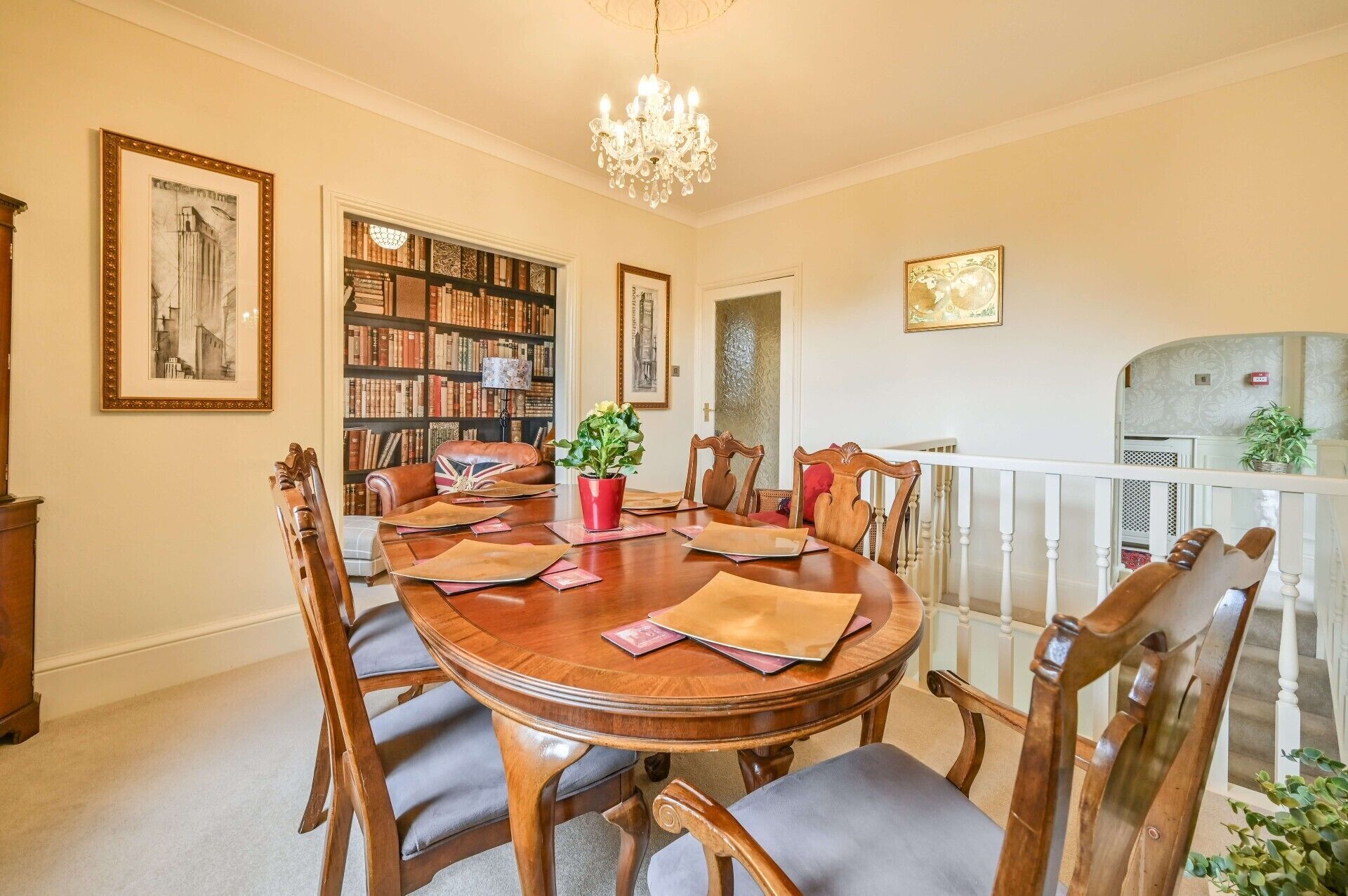 Comedor con mesa de madera, seis sillas, una araña, estantería y chimenea.