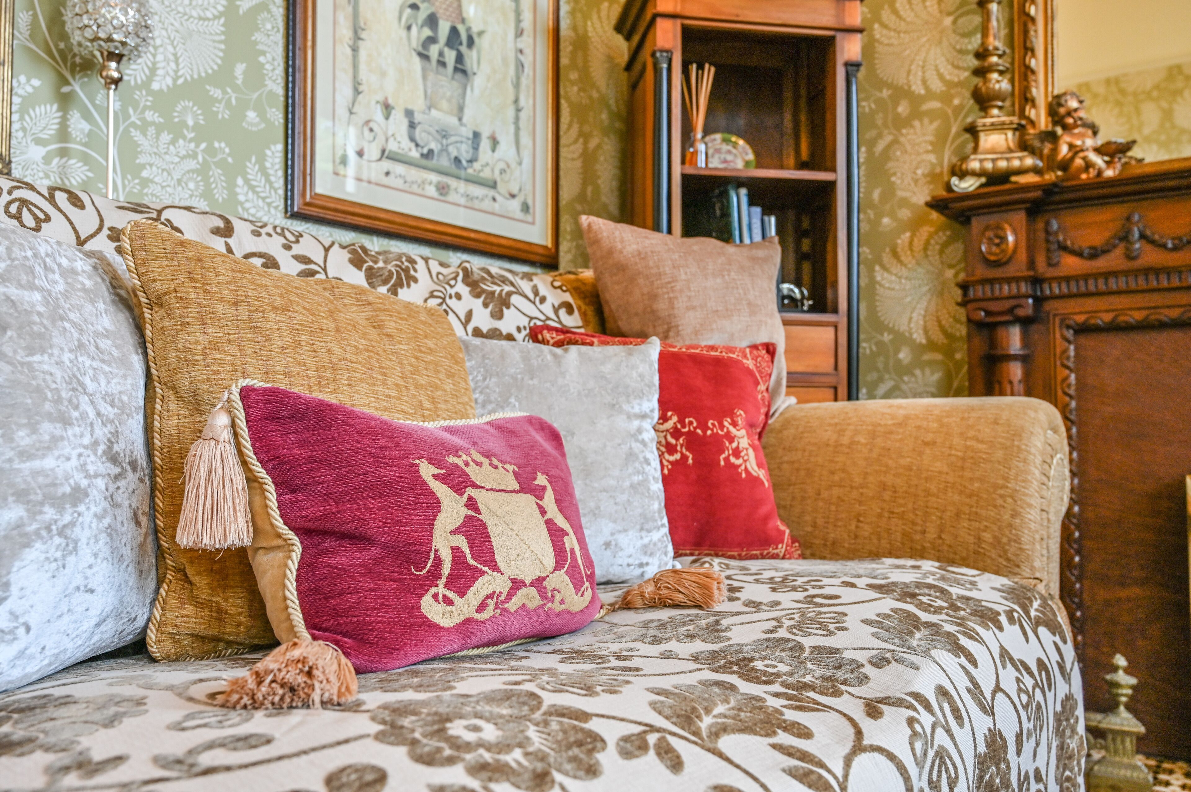 A room with a patterned sofa, a wooden cabinet, and a framed picture on the wall.