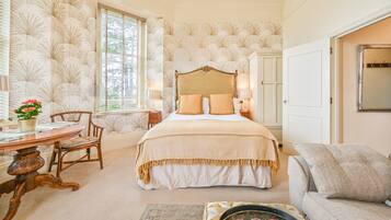 A bedroom with a large bed, a dining table with chairs, a sofa, and a decorative mirror.