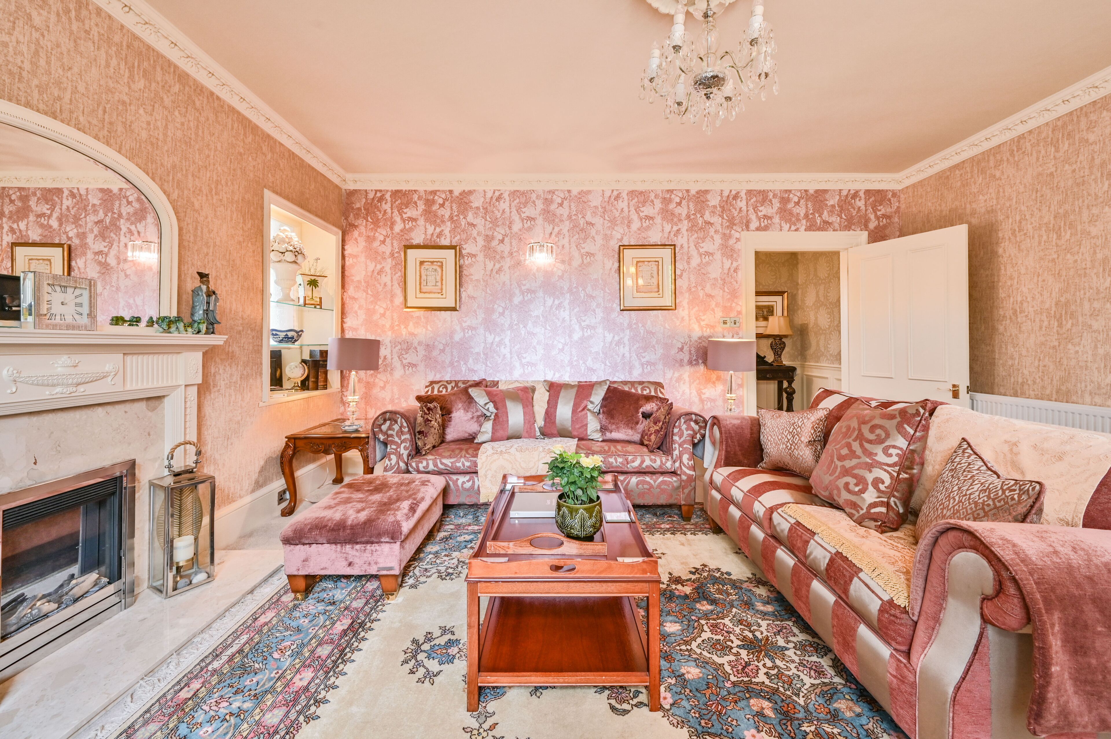 Ein Wohnzimmer mit Kamin, zwei Sofas, einem Couchtisch und einer Chandelier.