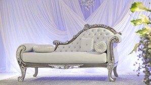 A white upholstered sofa with ornate metal legs and a tufted backrest, set against a draped fabric backdrop. - KT Hotels (Ouled Yaich)