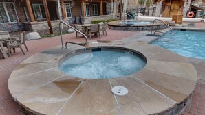 A hot tub with a stone edge, a pool, and outdoor seating. - Arapahoe Lodge 1 Bed 2 Bath (Keystone)