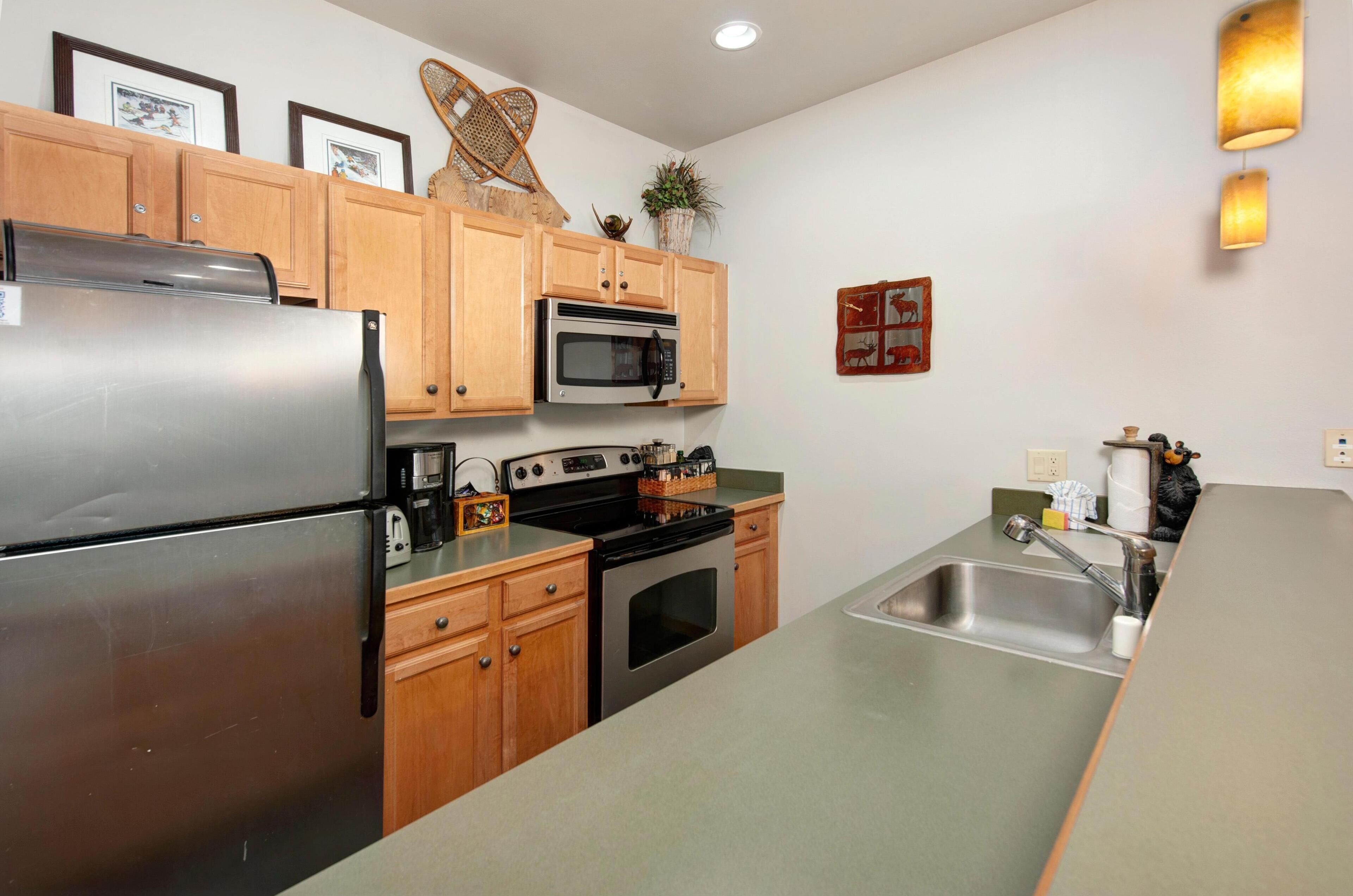 A kitchen with wooden cabinets, stainless steel appliances, a microwave, and a sink.