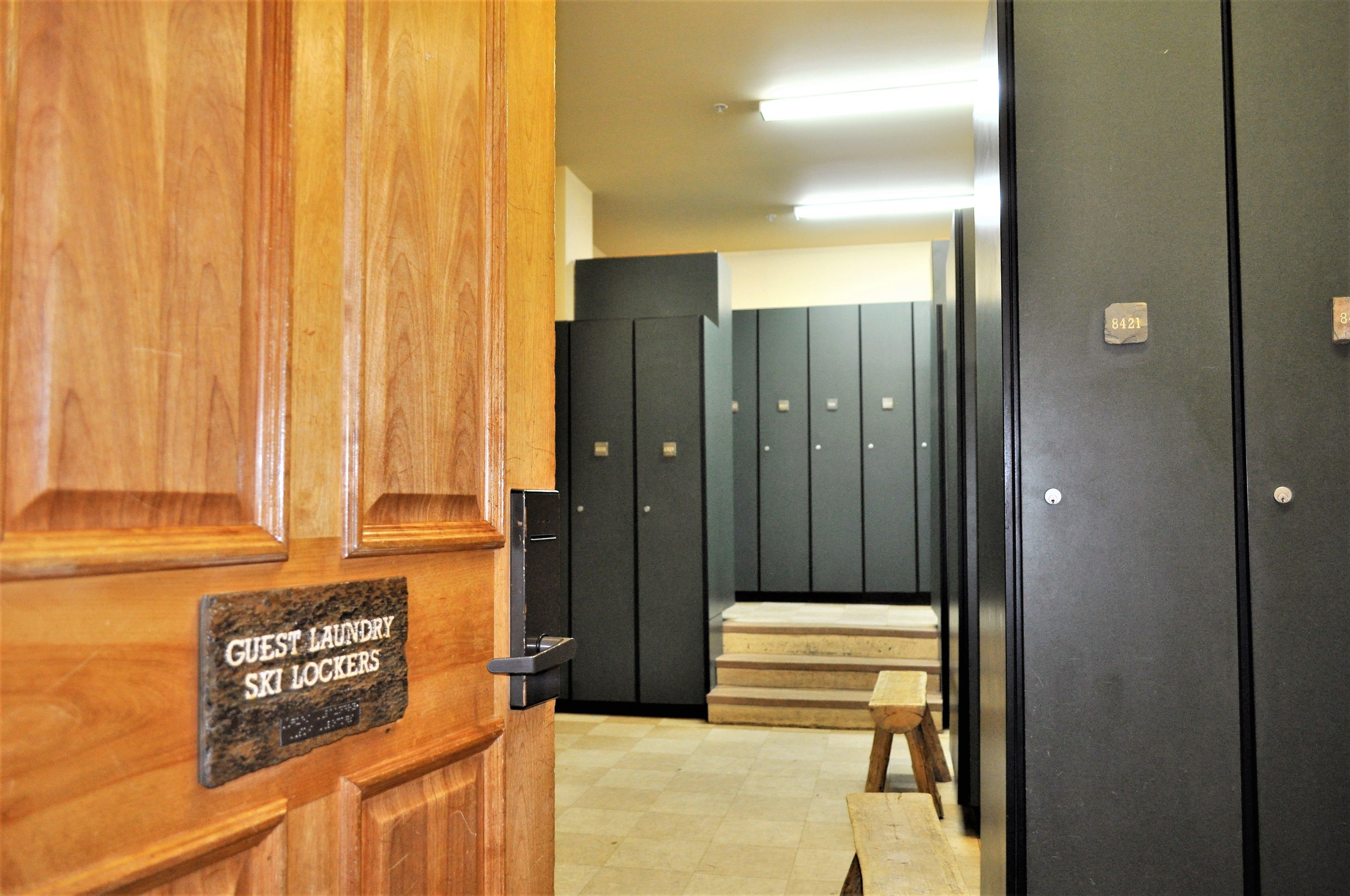 A hotel lobby with wooden paneling, a sign for guest laundry and ski lockers, and a row of black lockers.