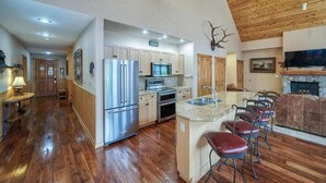 A modern kitchen with stainless steel appliances, a stone fireplace, and a wooden ceiling. - Buffalo Lodge 3 Bed 3 Bath (Keystone)