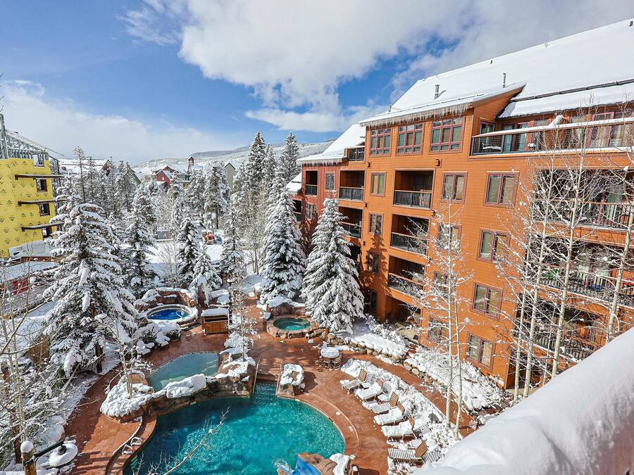 A resort with a pool area surrounded by snow-covered trees and buildings.