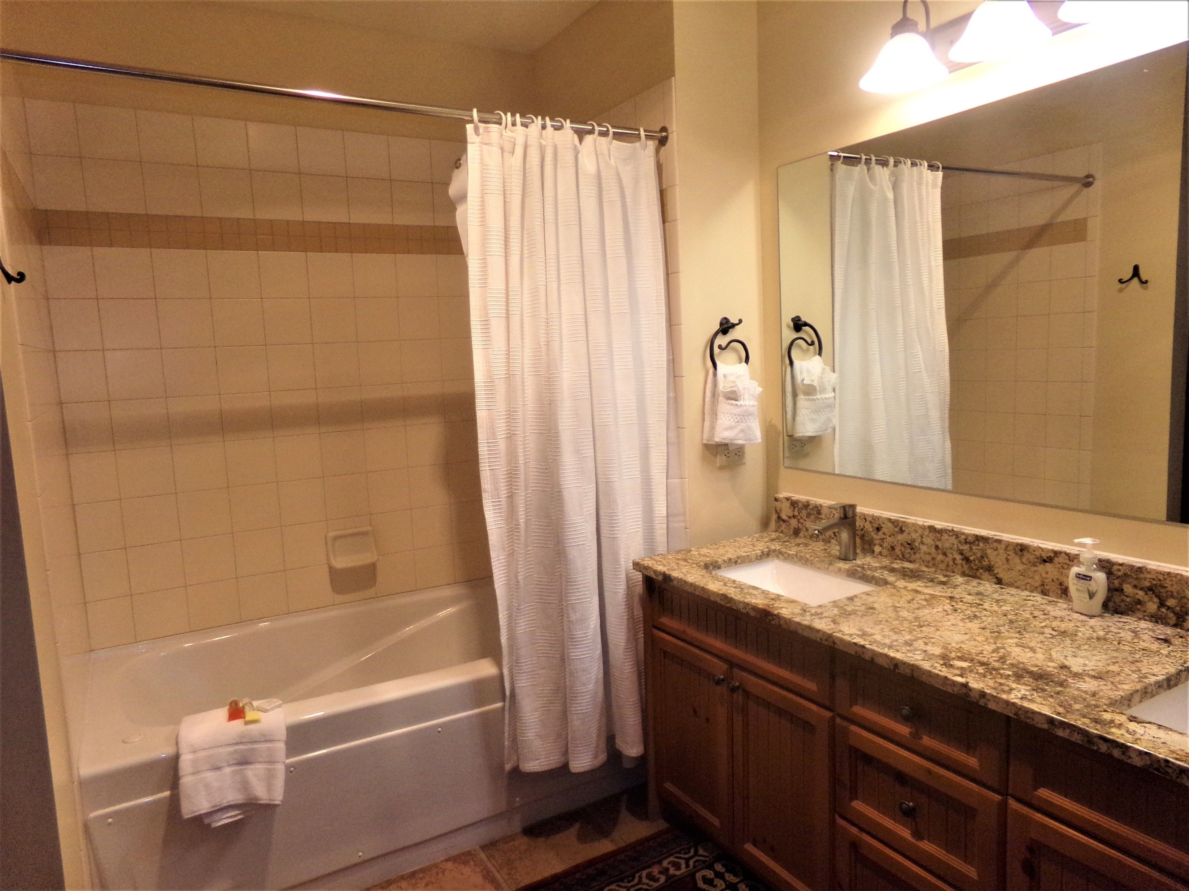 A bathroom with a bathtub, a sink, and a mirror.