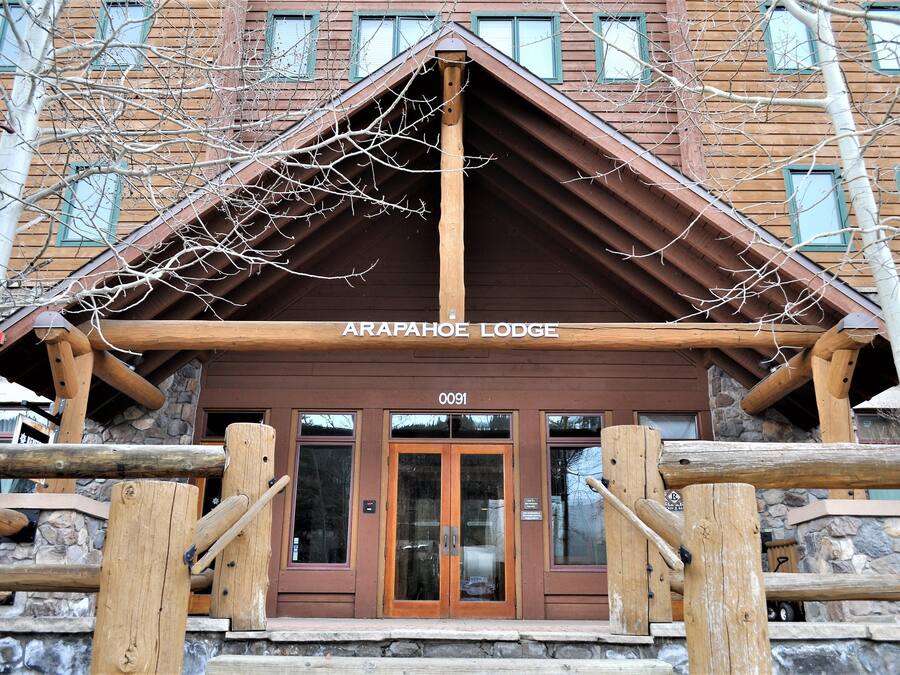 La entrada del Lodge Arapahoe con fachada de madera, detalles de piedra y vista despejada de las puertas de entrada.