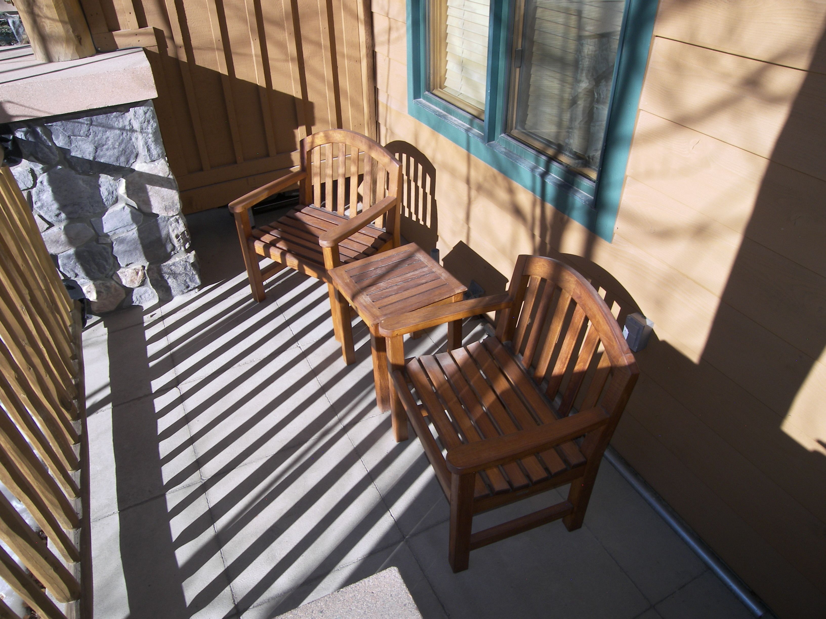 Une terrasse en bois avec un muret en pierre, une table et deux chaises.