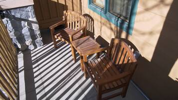 Une terrasse en bois avec un muret en pierre, une table et deux chaises.
