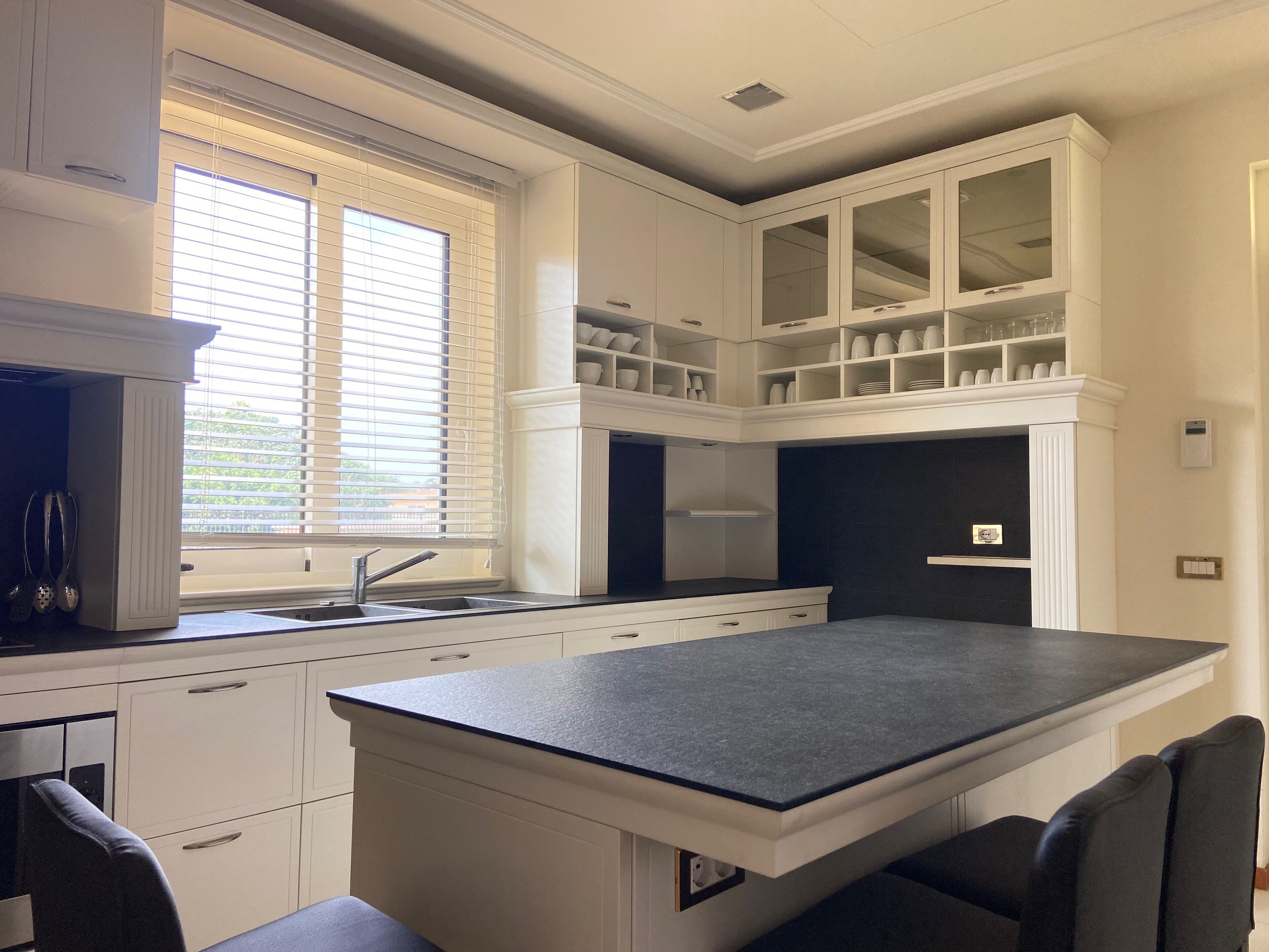A modern kitchen with white cabinetry, a black countertop, and a built-in island with seating.