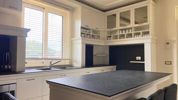 A modern kitchen with white cabinetry, a black countertop, and a built-in island with seating.