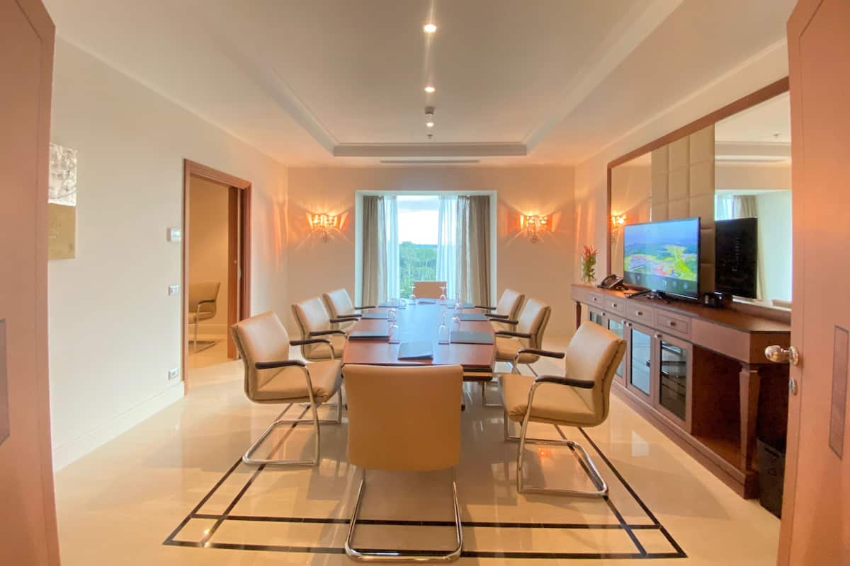 A conference room with a long table, chairs, a television, and a view of the outdoors.