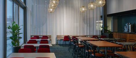 A modern dining area with tables and chairs, a bar area, and large windows.