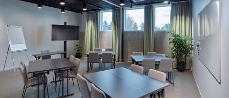 Un salón de conferencias con una gran mesa, sillas, una pizarra y un televisor.