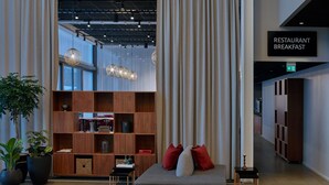 A modern interior with a sofa, a bookshelf, and a sign indicating a restaurant breakfast area.