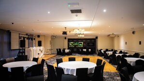 A conference room with round tables and chairs, a projector screen, and a large screen displaying a Christmas tree. - The Chase Hotel by Greene King Inns (Nuneaton)