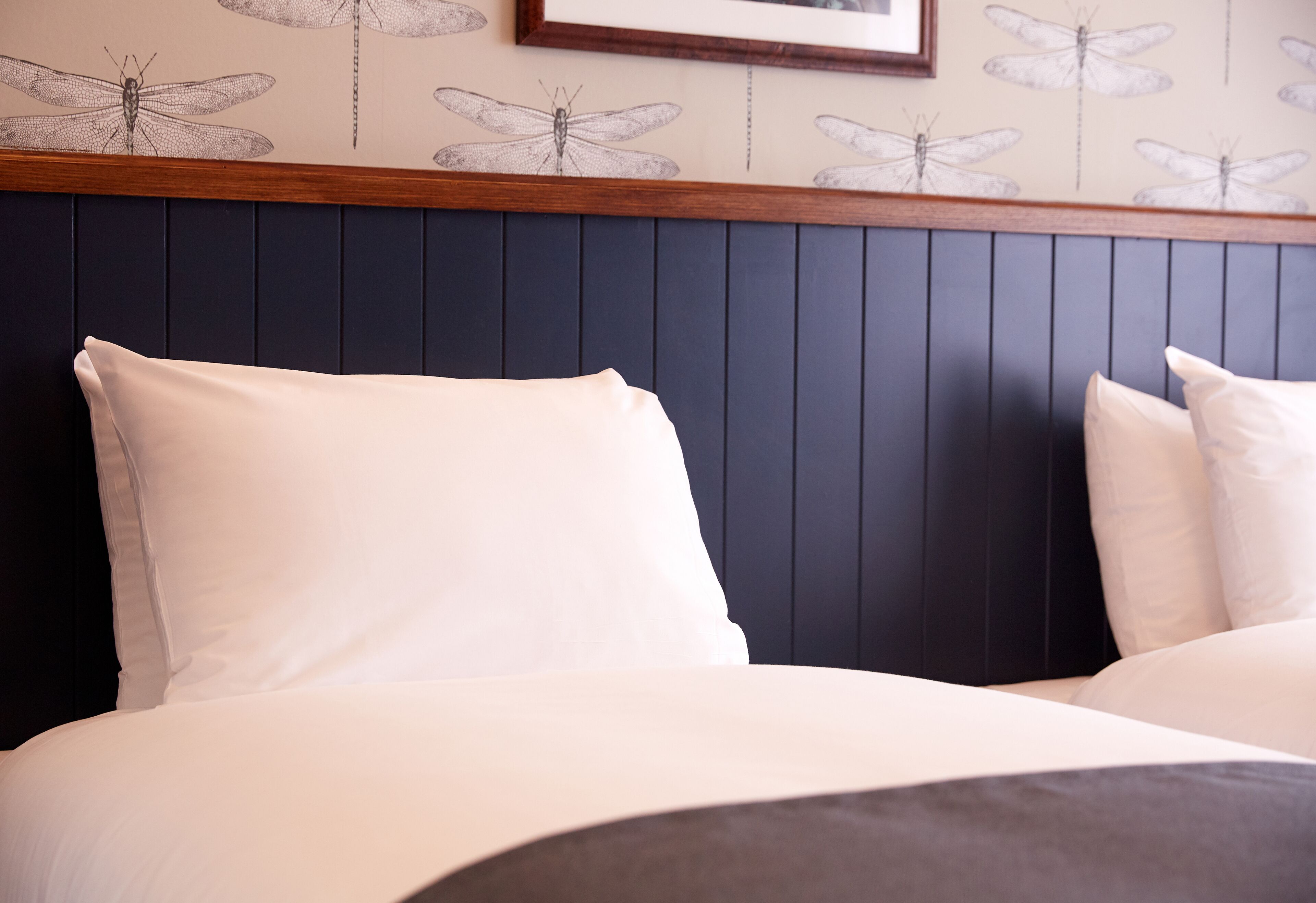 Una cama con ropa de cama blanca y un cabecero oscuro.