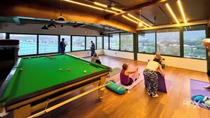 A pool table with balls, a yoga mat, and a person stretching. - Hotel Green View - Behind Pramarth Niketan (Yamkeshwar)