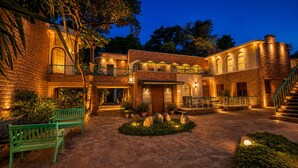 A courtyard with a brick building, green benches, and a stone fountain. - Hotel Inn Season - A Heritage Hotel in Jodhpur (Jodhpur)