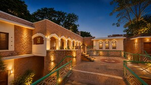 A courtyard with brick walls, arched windows, and green railings. - Hotel Inn Season - A Heritage Hotel in Jodhpur (Jodhpur)