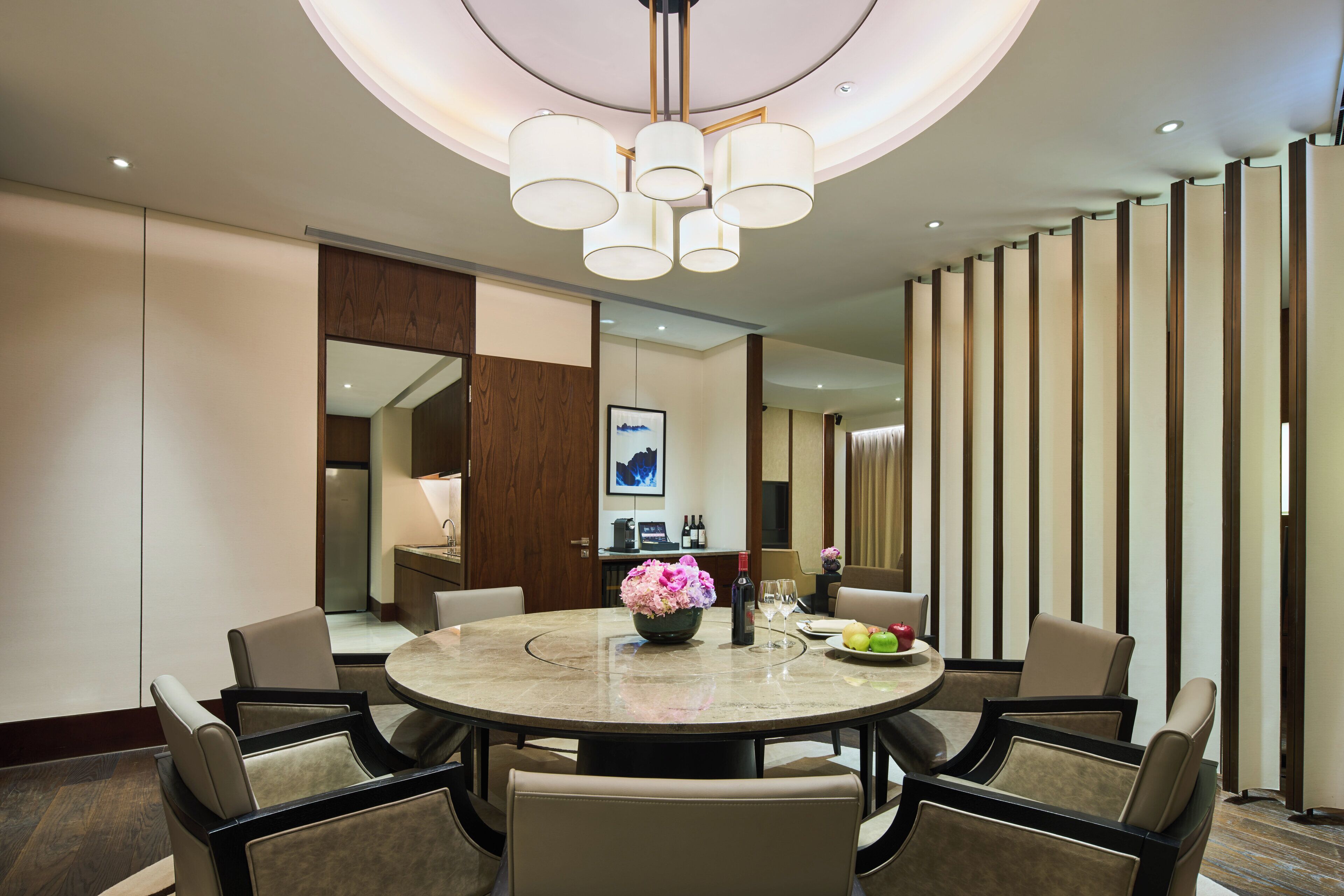 A modern dining area with a round table, chairs, and a chandelier.