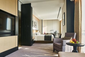 Habitación de hotel con cama, escritorio, silla, televisor y frutero.