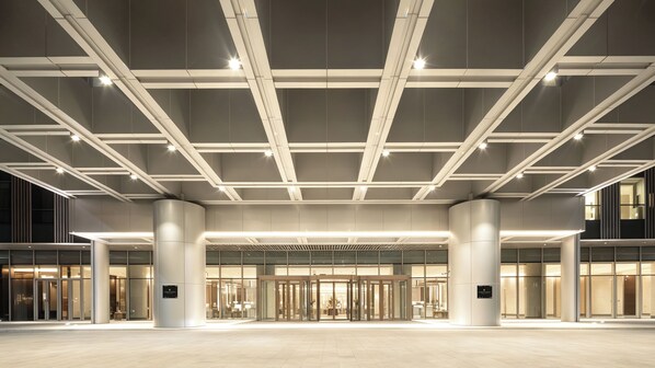 A modern hotel entrance with a glass facade, a central revolving door, and a ceiling with linear lighting fixtures. - InterContinental Shanghai Hongqiao NECC by IHG (Shanghai)