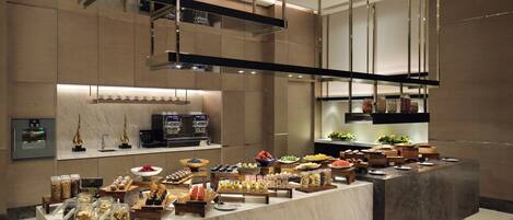 A modern kitchen with a marble countertop, built-in appliances, and a variety of food items displayed.