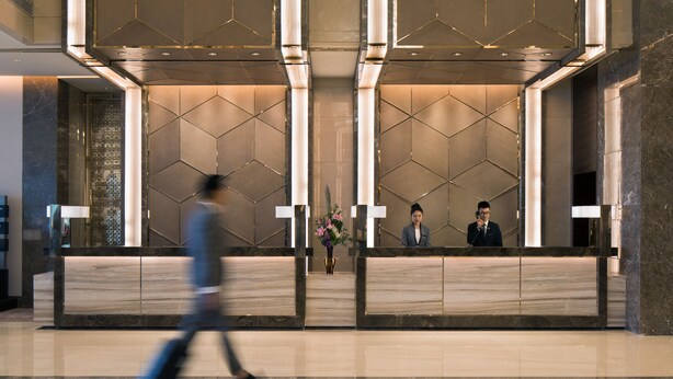 A modern reception area with a geometric patterned wall, a reception desk, and a polished floor. - InterContinental Shanghai Hongqiao NECC by IHG (Shanghai)