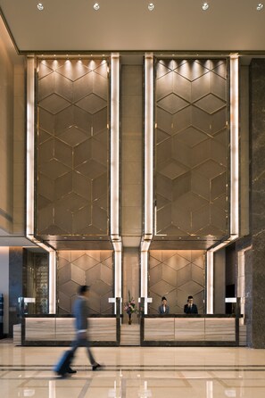 A modern reception area with a geometric patterned wall, a reception desk, and a polished floor. - InterContinental Shanghai Hongqiao NECC by IHG (Shanghai)