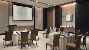 A conference room with multiple tables and chairs, a projector screen, and a podium. - InterContinental Shanghai Hongqiao NECC by IHG (Shanghai)