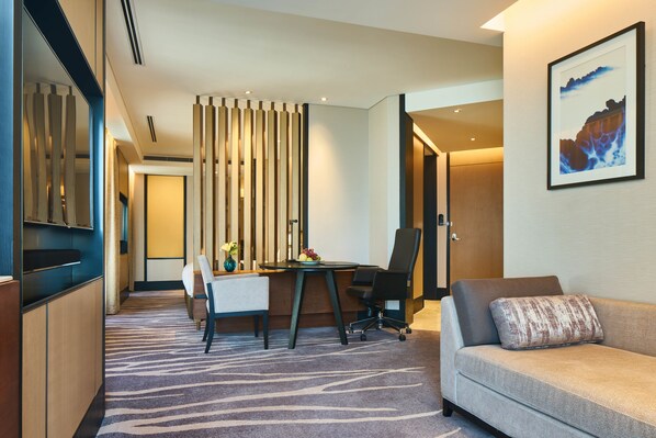 A modern hotel room with a desk, office chair, sofa, and a decorative wall piece. - InterContinental Shanghai Hongqiao NECC by IHG (Shanghai)