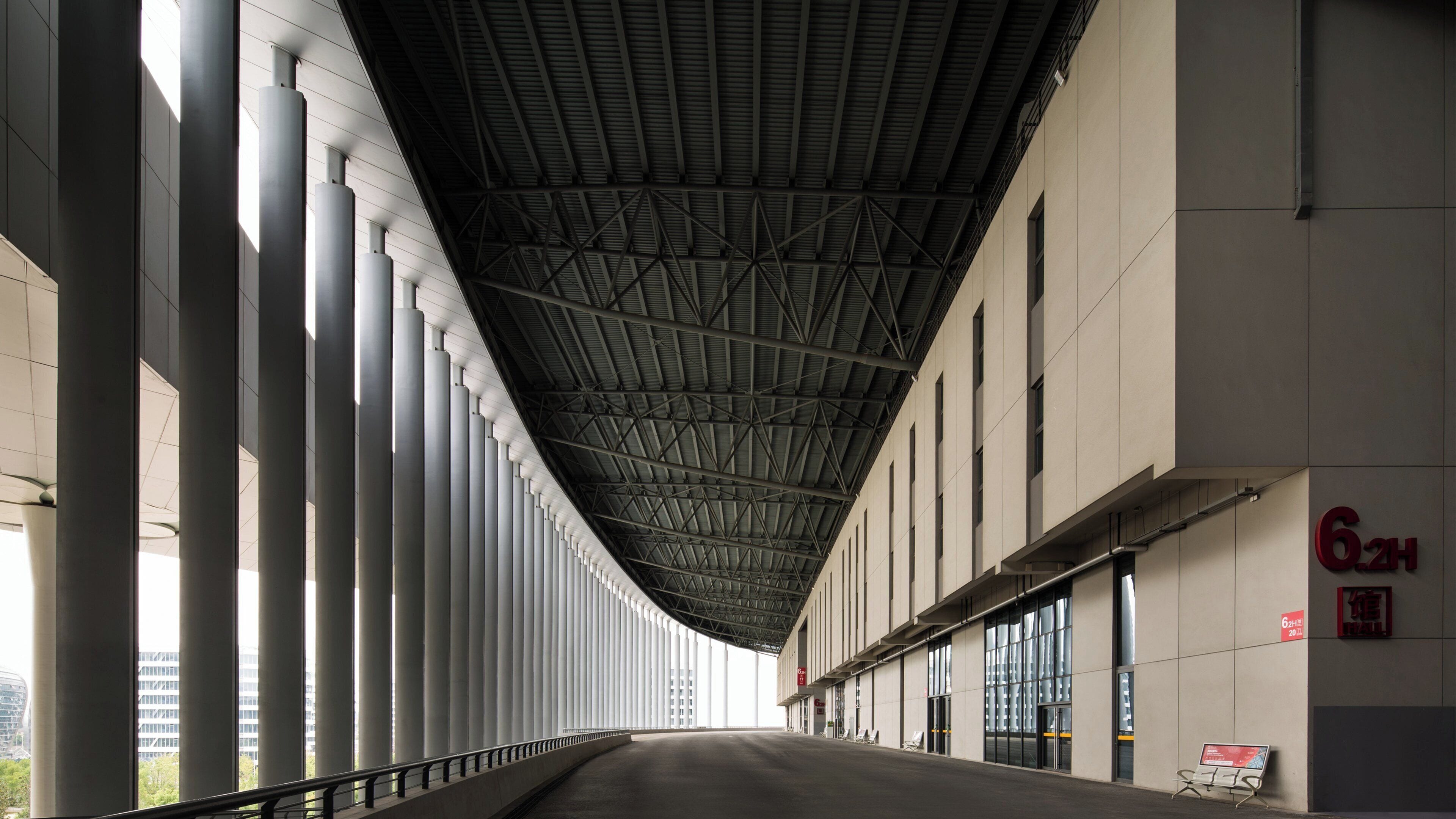 A modern building with a long corridor, large windows, and a metal roof structure.
